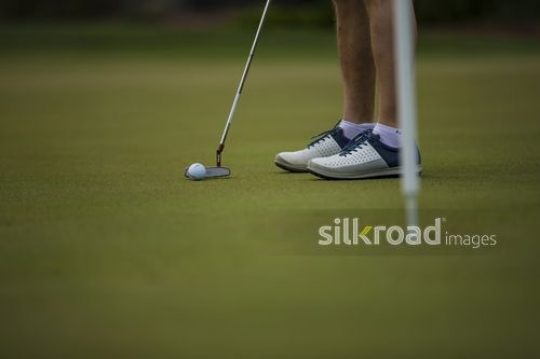 Man playing golf lines up his putt