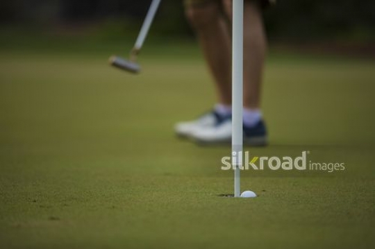Man scored the golf ball in the hole|-