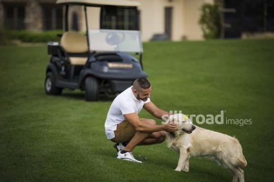 Arab man petting the dog with the Golf Cart in the background|-