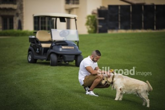 Young Middle Eastern man petting the dog|-