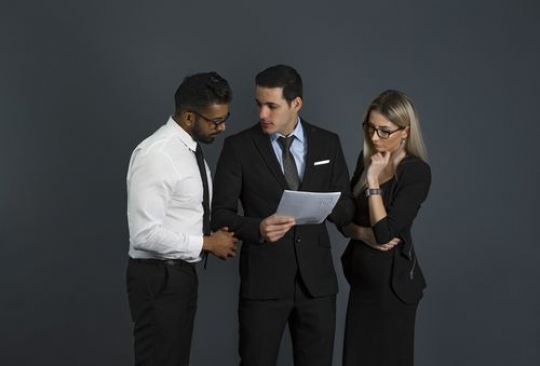 Business people looking at the paper and talking to each other|