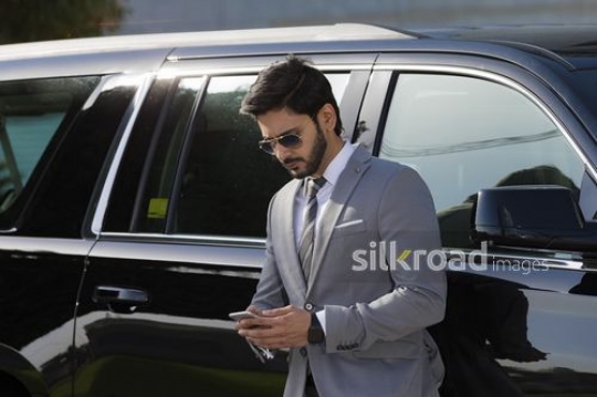 Medium Shot of a Businessman leaning on the car using his mobile|-