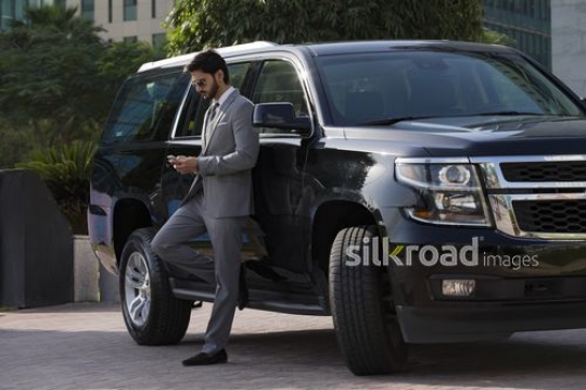 Businessman leaning on the car using his mobile|-