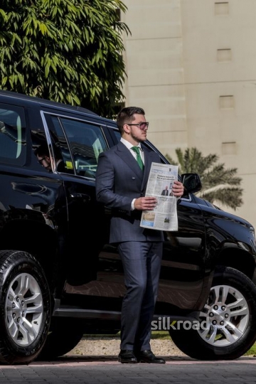 Western Businessman standing infront of his car with a newspaper |-