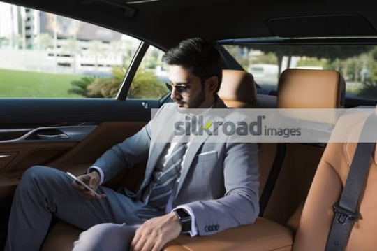 Expat Businessman sitting inside of the car using his mobile|