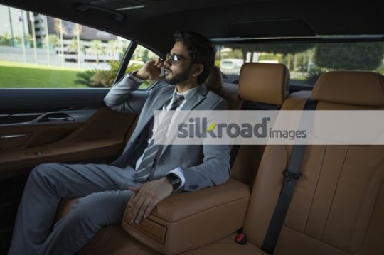 Expat Businessman sitting inside a luxury car talking on the phone|