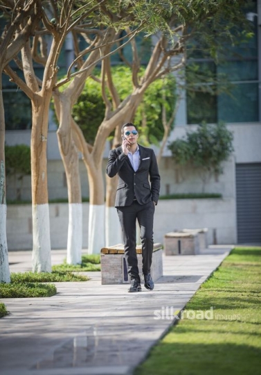 Businessman walking and using his mobile|-