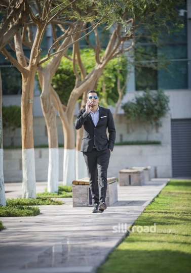 Arab Businessman walking using his mobile|-
