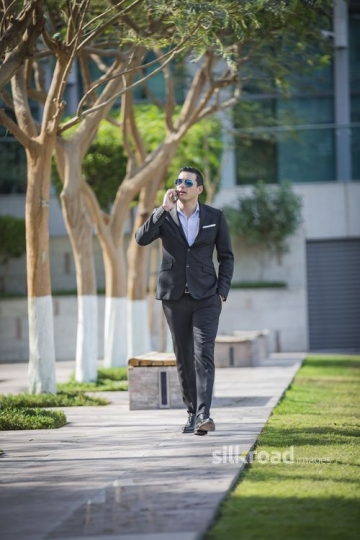 Middle Eastern Businessman walking using his mobile|-