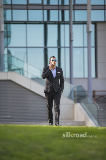 Arab Businessman walking and using his mobile|-
