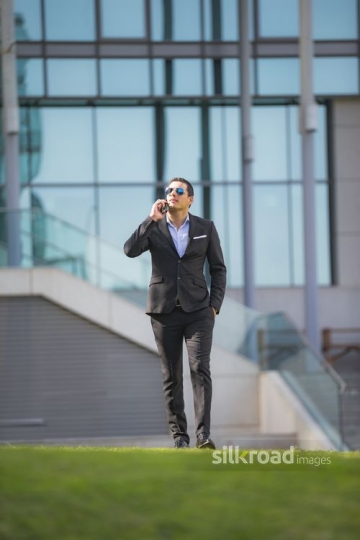 Middle Eastern Businessman walking and talking on the phone|-