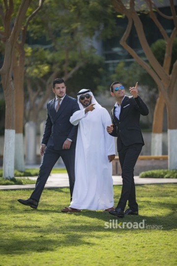 Middle Eastern Businessmen pointing and the Western Businessman is walking next to them|-