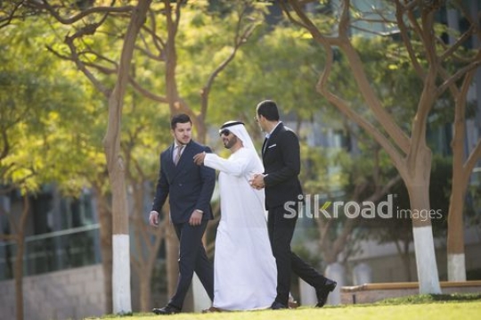 Two Businessmen dressed in suits looking at the Arab Businessman in the middle|-