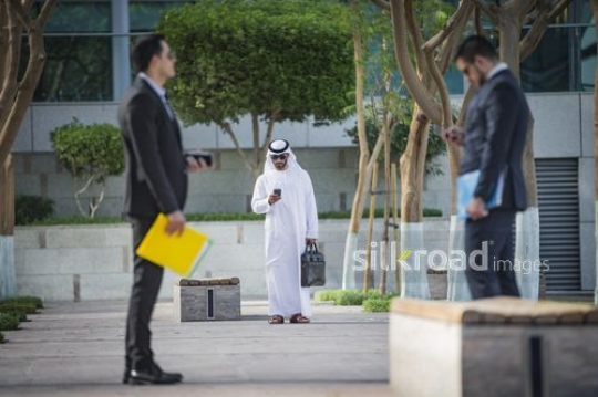 Businessmen standing using their devices|-