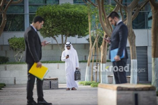 Group of Businessmen standing using their mobiles|-