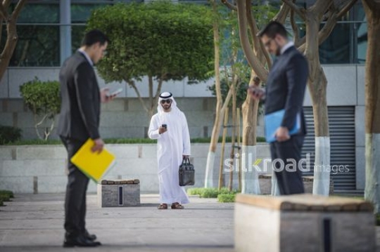 Group of Businessmen standing outside using their mobiles|-