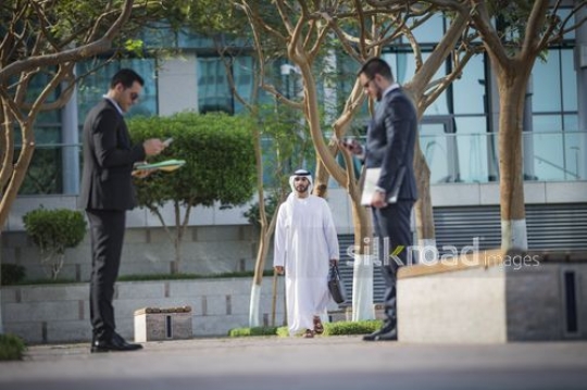 Middle Eastern businessman walking towards his colleagues|-
