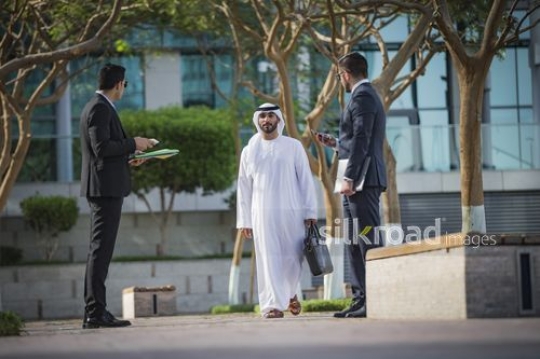 Middle Eastern businessman walking towards his colleagues|-