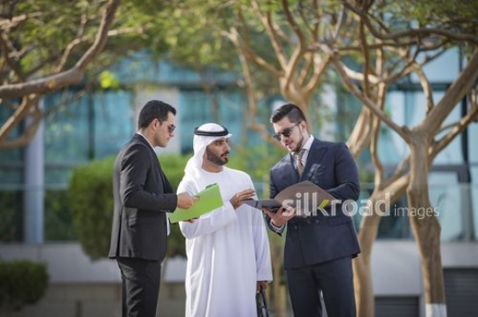 Middle Eastern Businessman standing outside talking to his colleagues|-