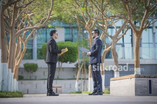 Businessmen standing talking to each other|-