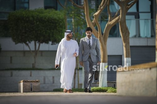 Businessmen walking outside together|-