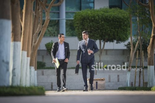 Middle Eastern and Western Businessman walking together|-
