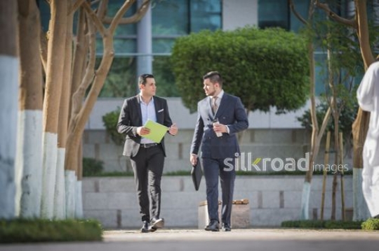Middle Eastern and Western man dressed in Business suits walking together |-