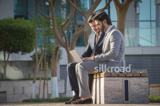 Two Employees sitting on the bench together working from the laptop|-