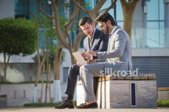 Western Businessman sitting with his colleague outside working|-