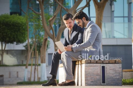 Businessmen sitting outside working|-
