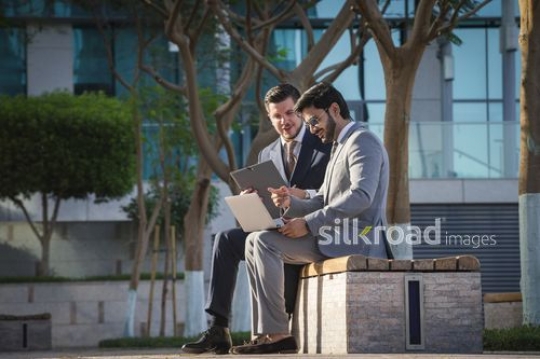 Western Businessman sitting with his colleague outside working together|-