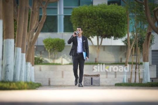 Arab businessman walking and drinking coffee|-