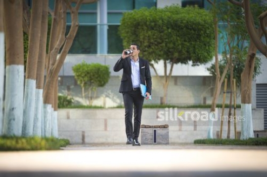Middle Eastern businessman drinking from his travel mug|-