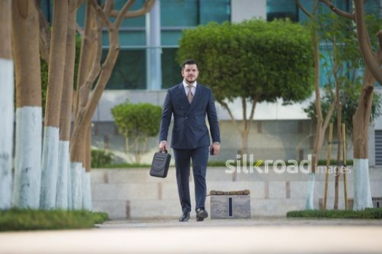 Businessman walking outside with a laptop bag|-
