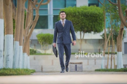 Western Businessman walking with a laptop bag|-