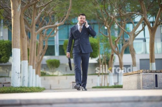 Businessman walking and having a phone call|-