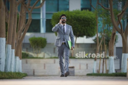 Business man walking while having a phone call|-