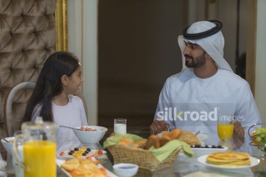 Middle Eastern man sitting with his daughter having breakfast|