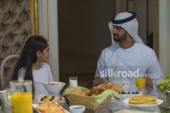 Arab father and daughter sitting together during breakfast|