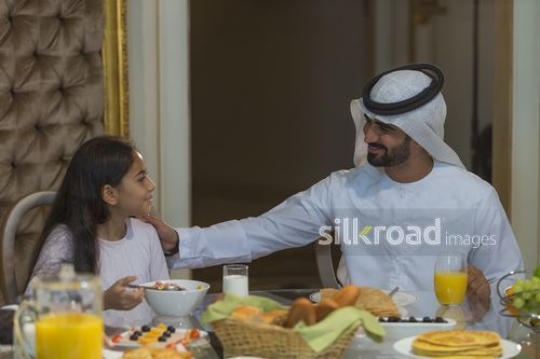 Middle Eastern man sitting with his daughter having breakfast|