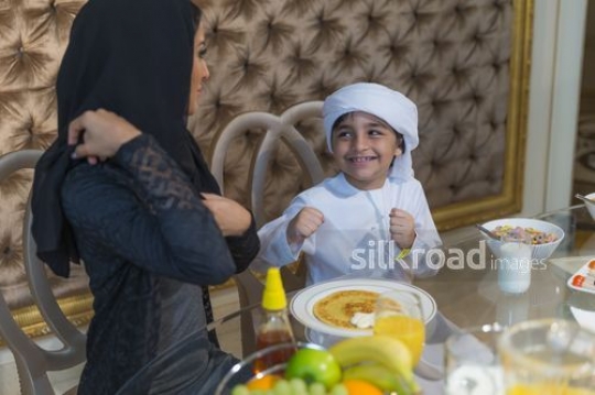 Young arab boy bonding with his mother during breakfast |