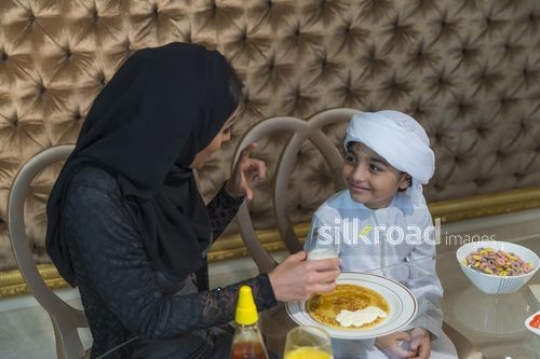 Middle Eastern woman sitting with the young boy bonding|