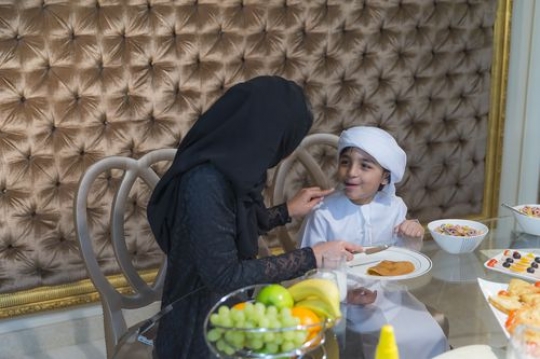 Arab mother feeding her son breakfast|-
