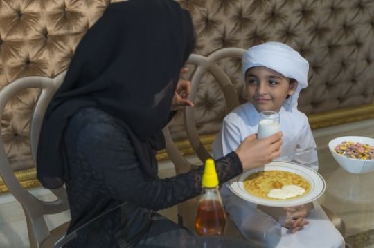 Arab mother giving her son a cup of milk|-