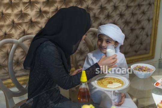 Middle Eastern mother giving her son milk to drink|