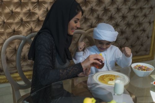 Arab son sitting with his mother and excited to have breakfast|-