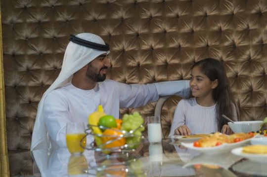Arab father and daughter sitting together|-