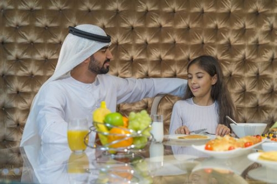 Arab father and daughter sitting together|-