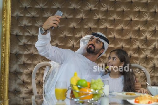Middle Eastern man taking a picture with the little girl|
