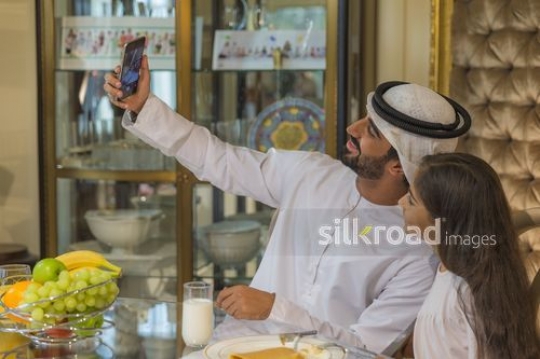 Middle Eastern father and daughter taking a selfie together|